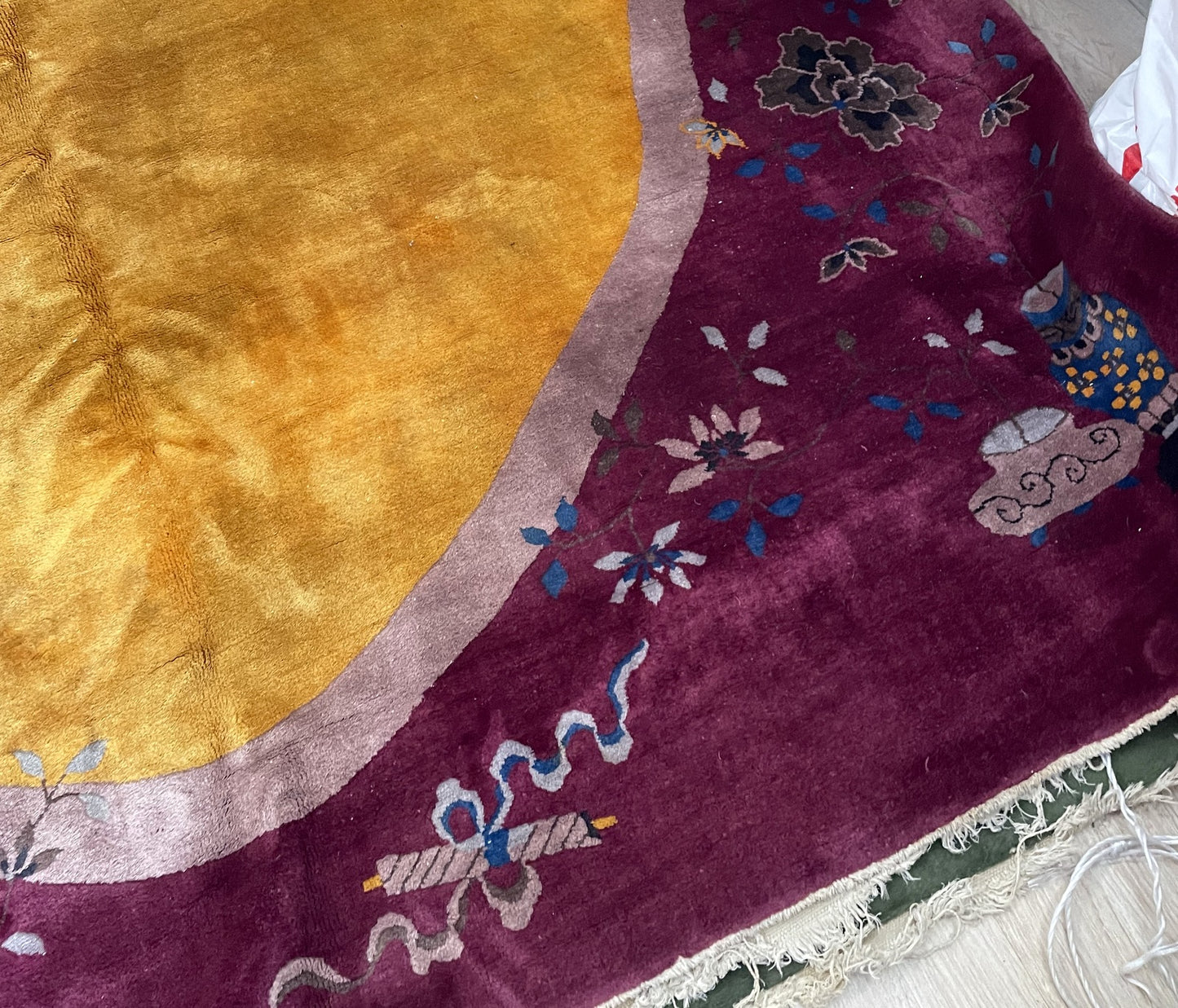 Close-up of a foo lion motif in cobalt blue and saffron gold on a 1920s Chinese Art Deco rug, with scattered cherry blossom petals and butterflies.

