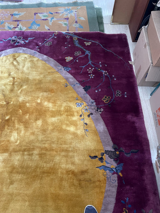 Close-up of a near-mint condition 1920s Chinese Art Deco carpet showing a burnished gold oval medallion, trailing wisteria blossoms, and a cobalt blue foo lion.

