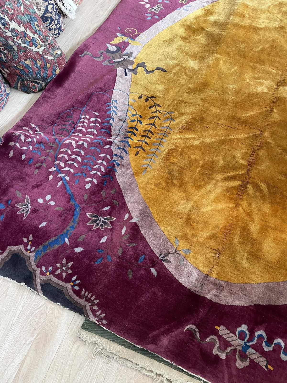 Detail of the oval medallion and surrounding motifs on a vintage Chinese Art Deco rug, including white and powder-blue wisteria cascading across the upper field.

