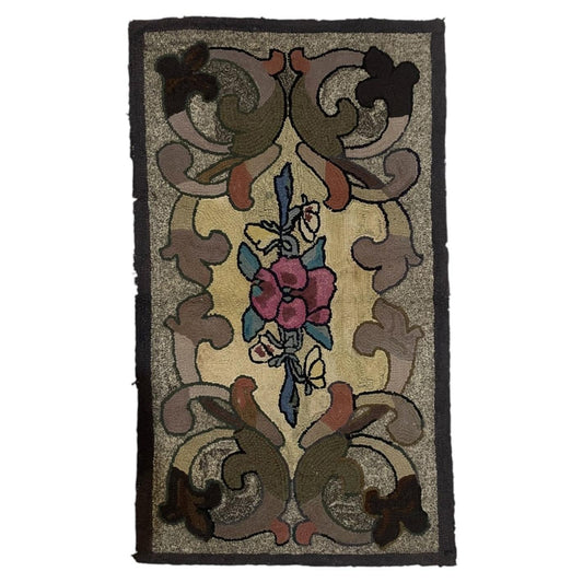 Full view of an antique American hand-hooked wool rug from the early 1900s featuring a central bouquet of deep magenta and crimson roses with teal leaves, a hovering butterfly, and sweeping acanthus scrolls in olive, taupe, and terracotta.

