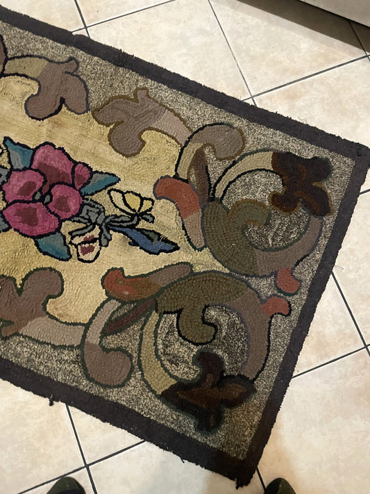 Close-up of a folk art American hooked rug showing a golden-ivory field, bold black-outlined roses, and interlocking acanthus scrolls with a solid deep charcoal border.

