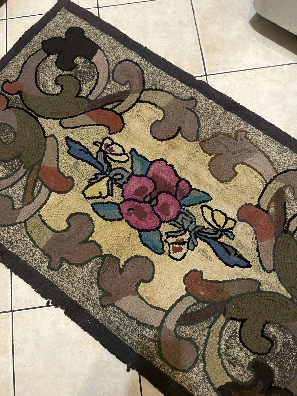 Charming early 1900s American folk art rug with a central rose bouquet, teal-blue stems and leaves, a delicate butterfly, and vigorous curvilinear acanthus scrolls in muted earth tones.

