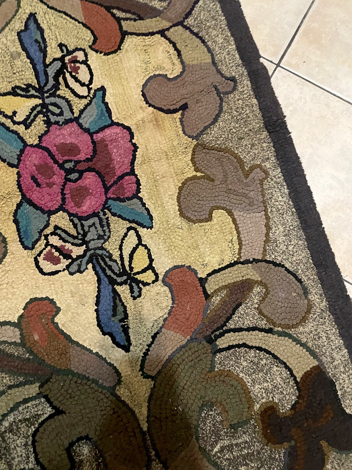 Full perspective of a folk art American hooked rug with a bold graphic design of roses, acanthus scrolls, and a butterfly, framed by a solid charcoal outer border.

