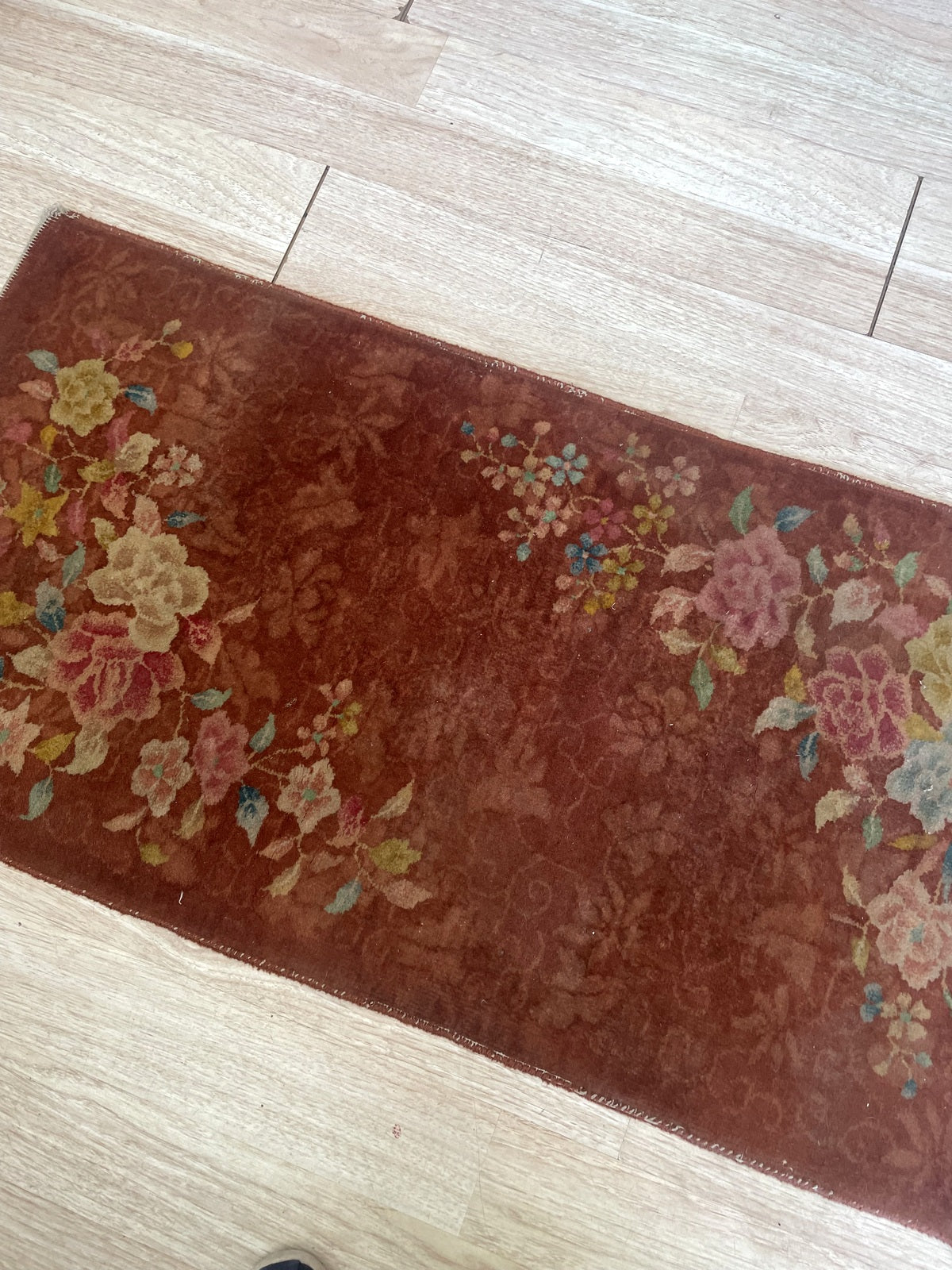 Tone-on-tone floral scrollwork across the rust-red ground