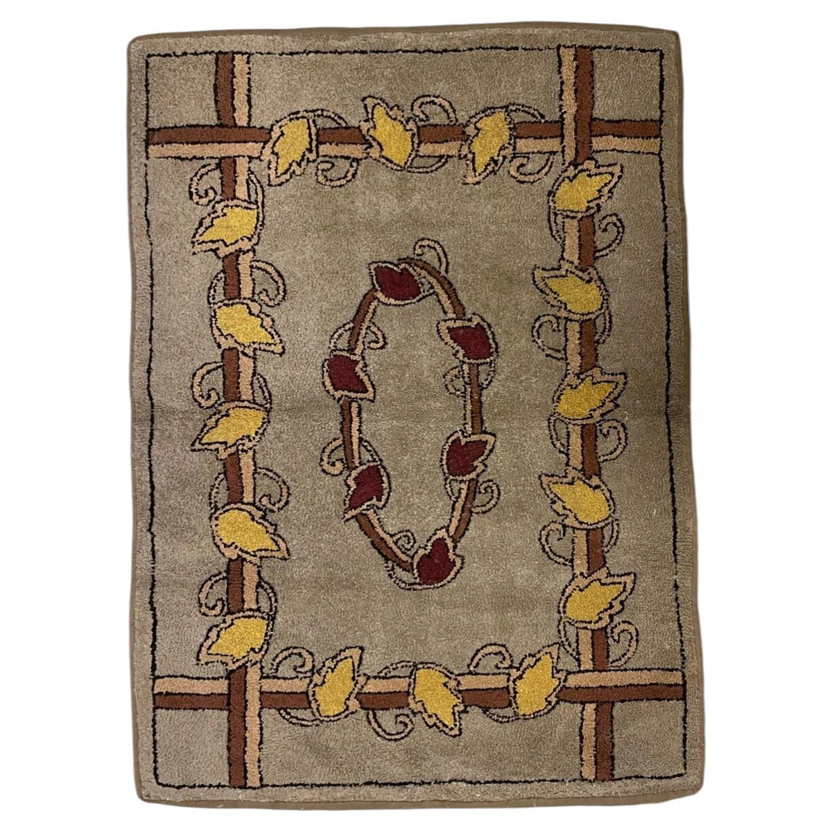 American hooked wool rug with a burgundy oval leaf wreath and golden-yellow leafy trellis frame.