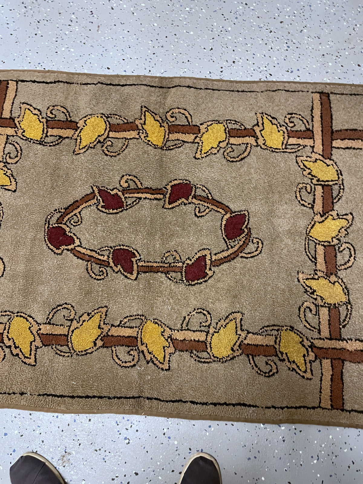Angled view of the yellow leaf border and burgundy wreath on the hooked wool rug.