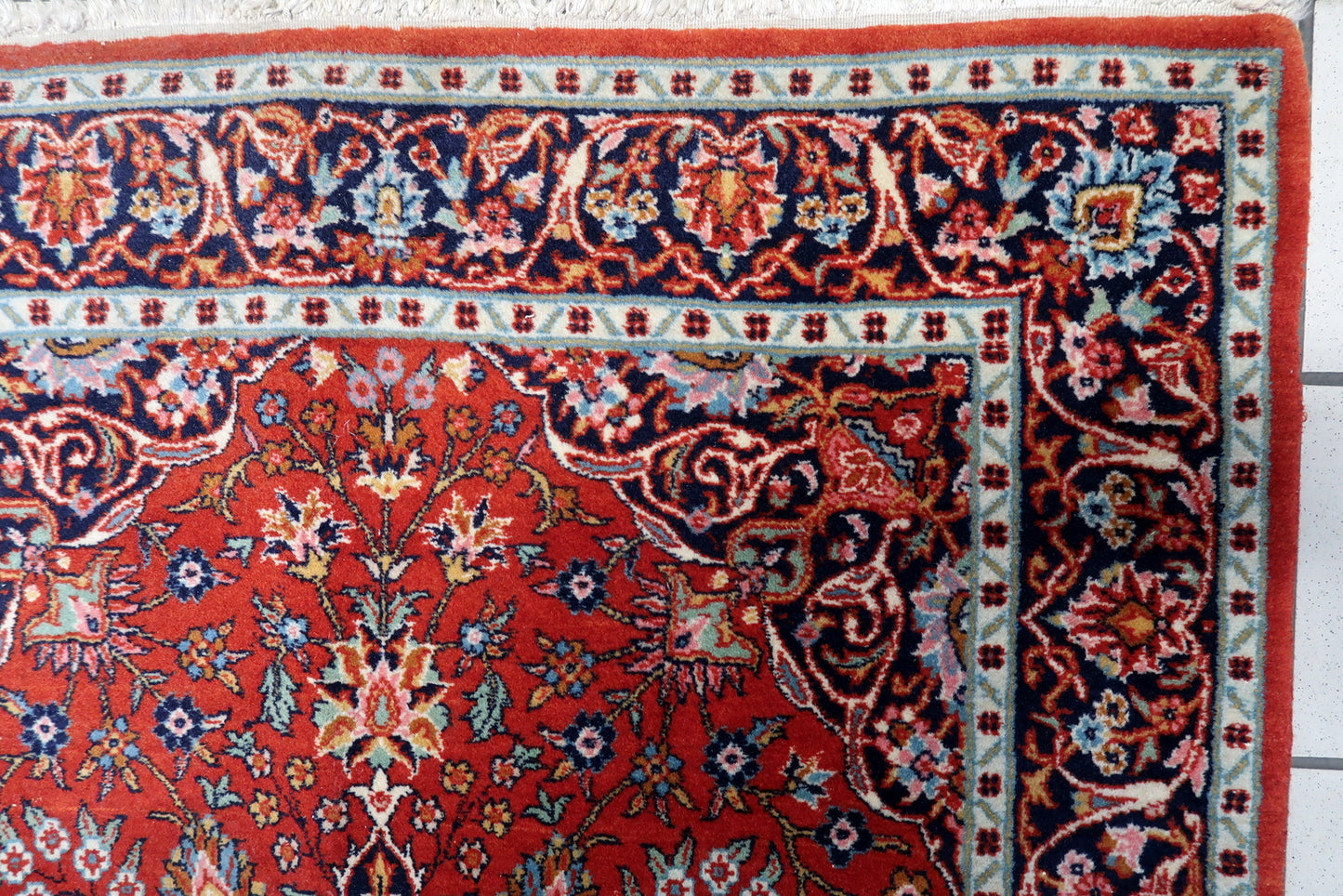 Close-up of intricate floral patterns and vibrant colors on the antique Persian Kashan rug.