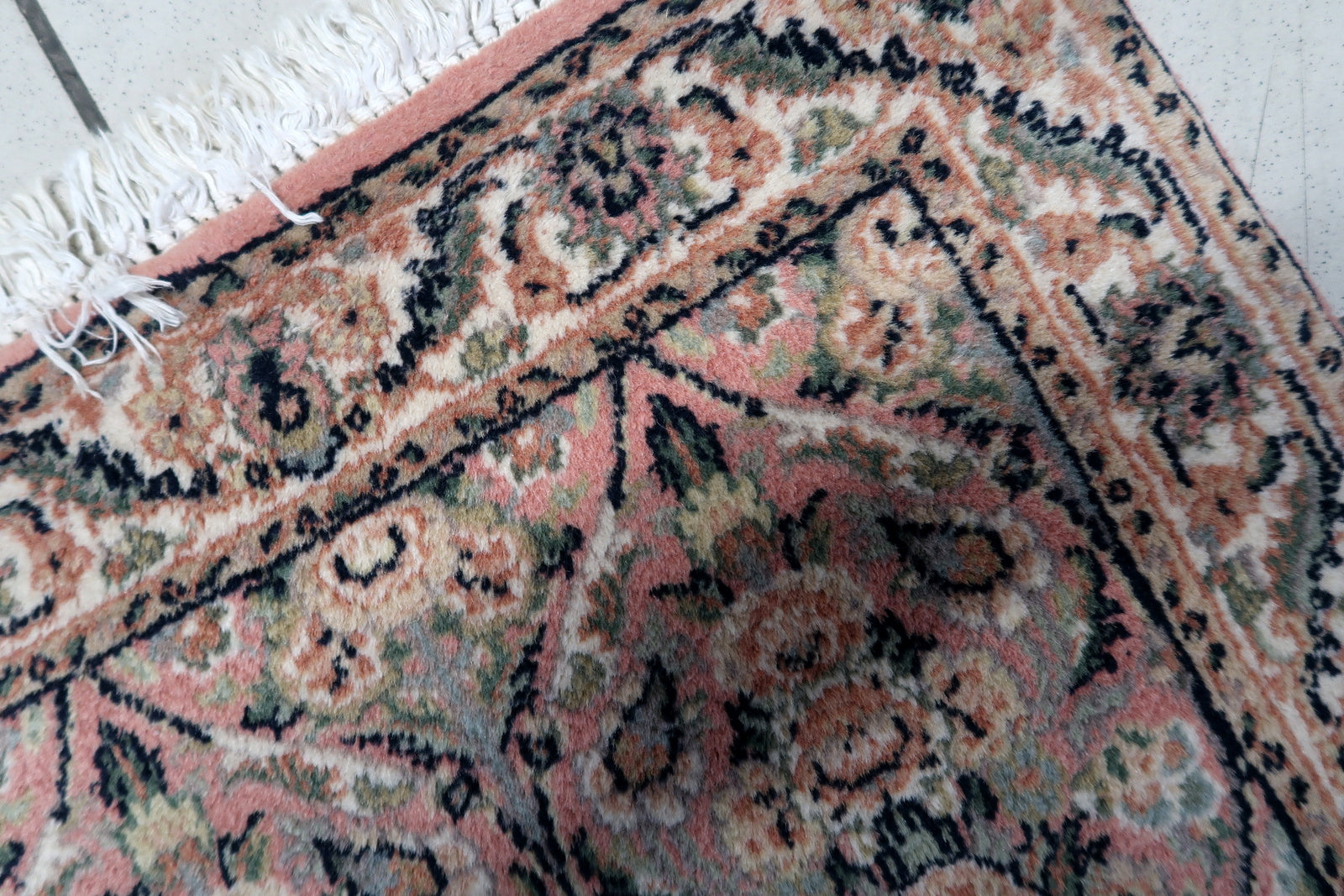 Close-up of the detailed patterns and pastel pink hues on the handmade vintage Persian Kerman rug.