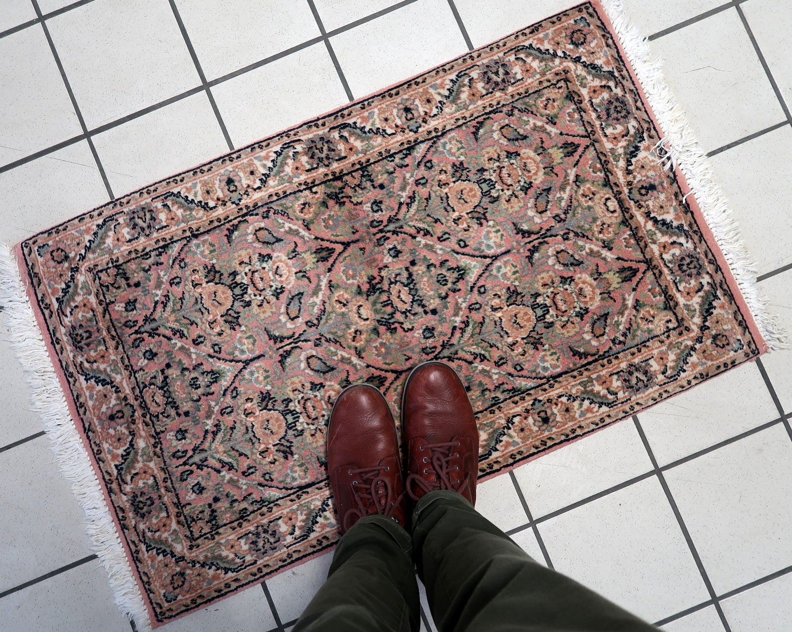 Close-up of the pastel pink floral motifs on the vintage Persian Kerman rug.