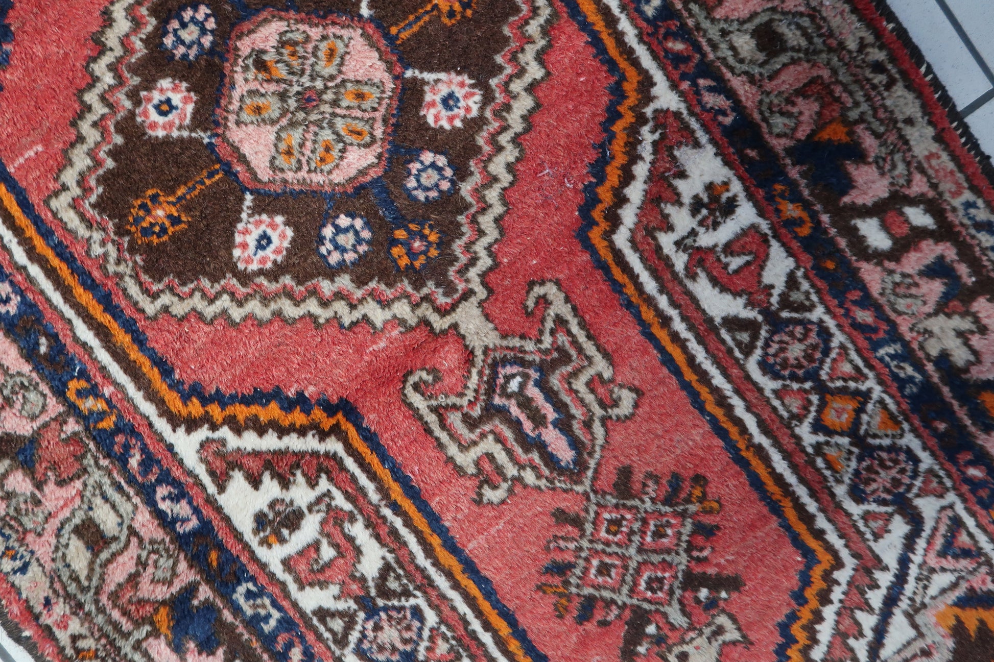 Close-up of the rich chocolate brown background and traditional design elements on the rug