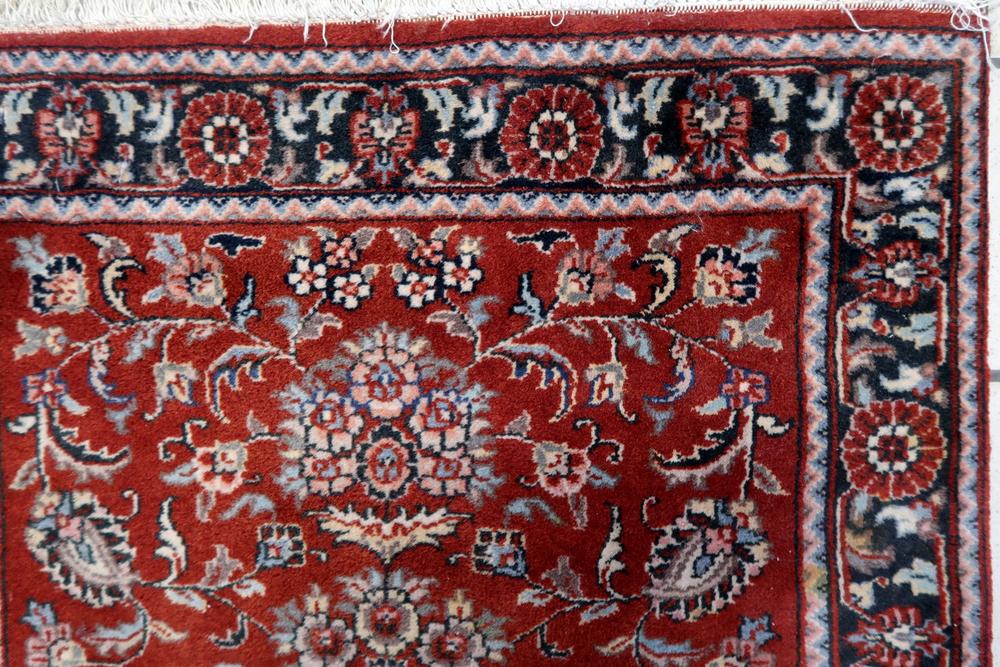 Close-up of the elegant arch-like design and delicate tassel motifs on the rug's surface