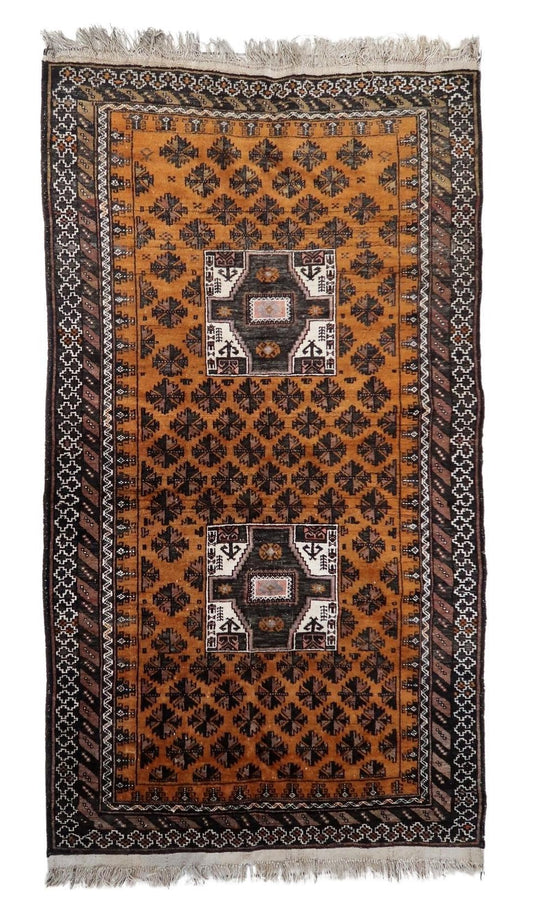 Handmade antique Afghan Baluch rug showcasing intricate geometric patterns on a warm amber background