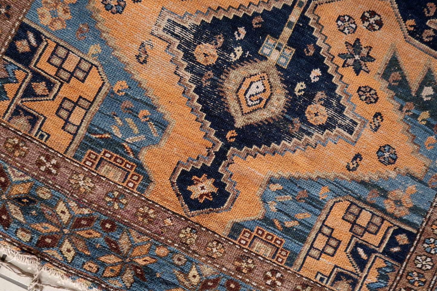 Close-up of faded colors on Handmade Antique Caucasian Shirvan Rug - Detailed view showcasing the gracefully faded deep blues, warm oranges, and neutral tones.