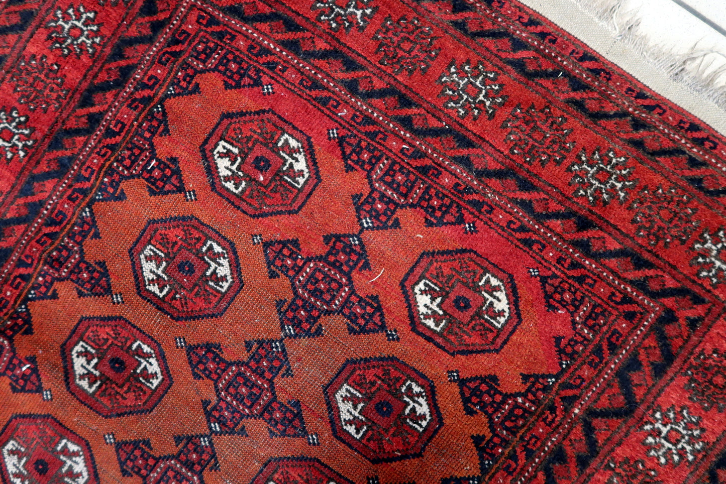 Close-up of red hues on Handmade Antique Afghan Baluch Rug - Detailed view highlighting the vibrant red color dominating the rug.