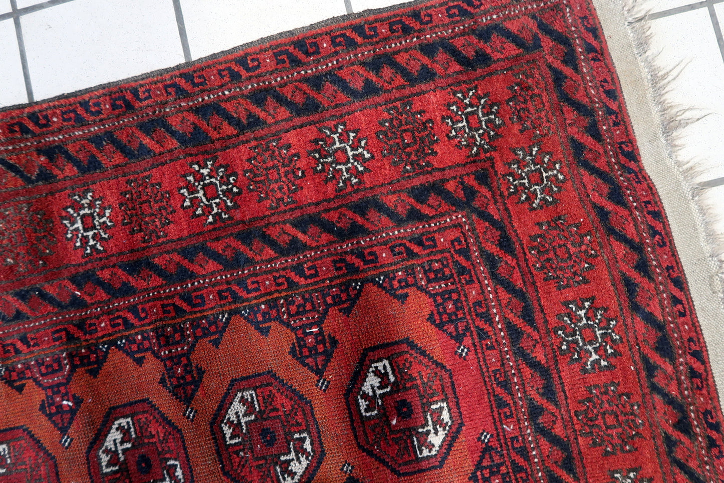 Close-up of low pile texture on Handmade Antique Afghan Baluch Rug - Detailed view emphasizing the vintage charm of the rug's low pile texture.