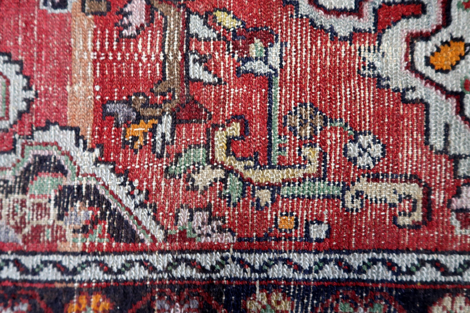 Close-up of an intricately designed rug with red, white, and black patterns.