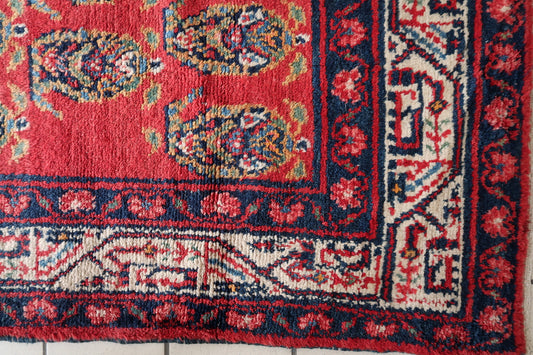 Close-up detail of a single geometric medallion in navy blue and ivory on the red field.

