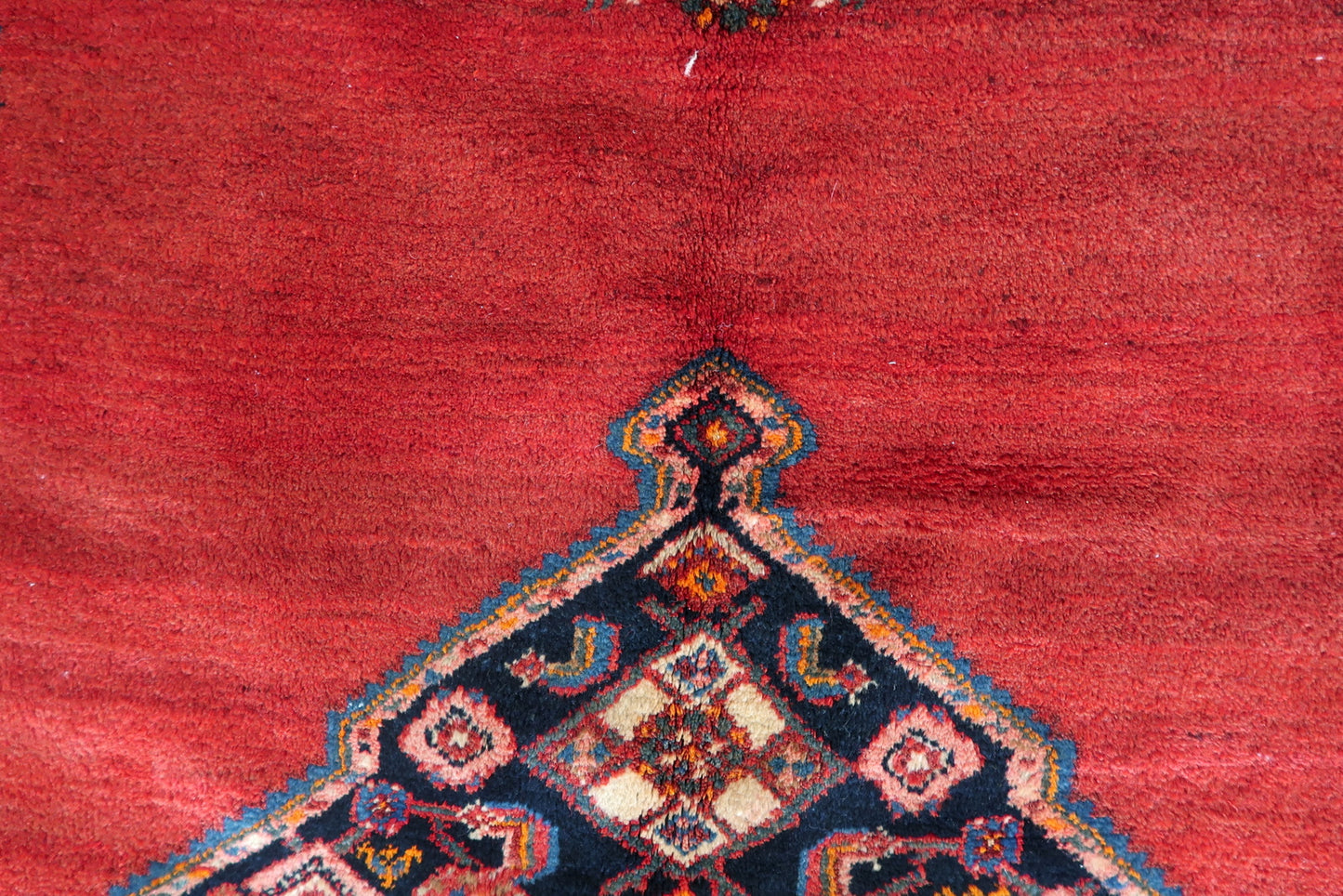 Contrast between the vibrant red field and dark blue geometric patterns.

