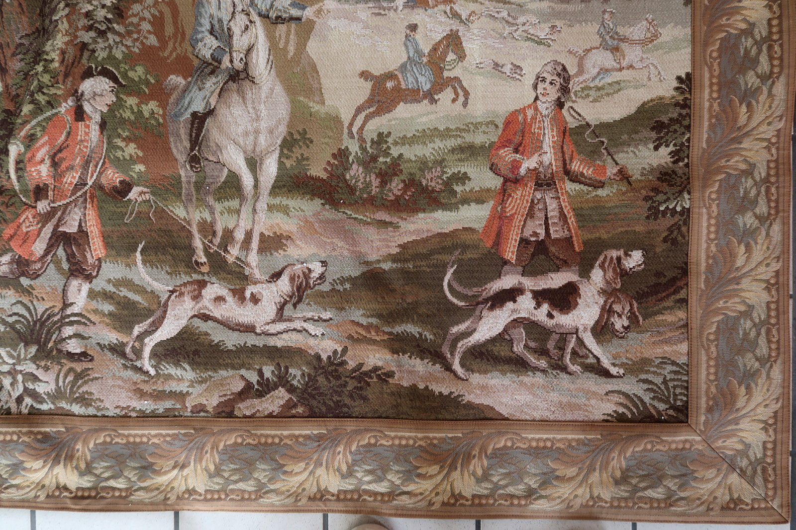 Close-up of huntsmen in red coats on horseback in a forest.

