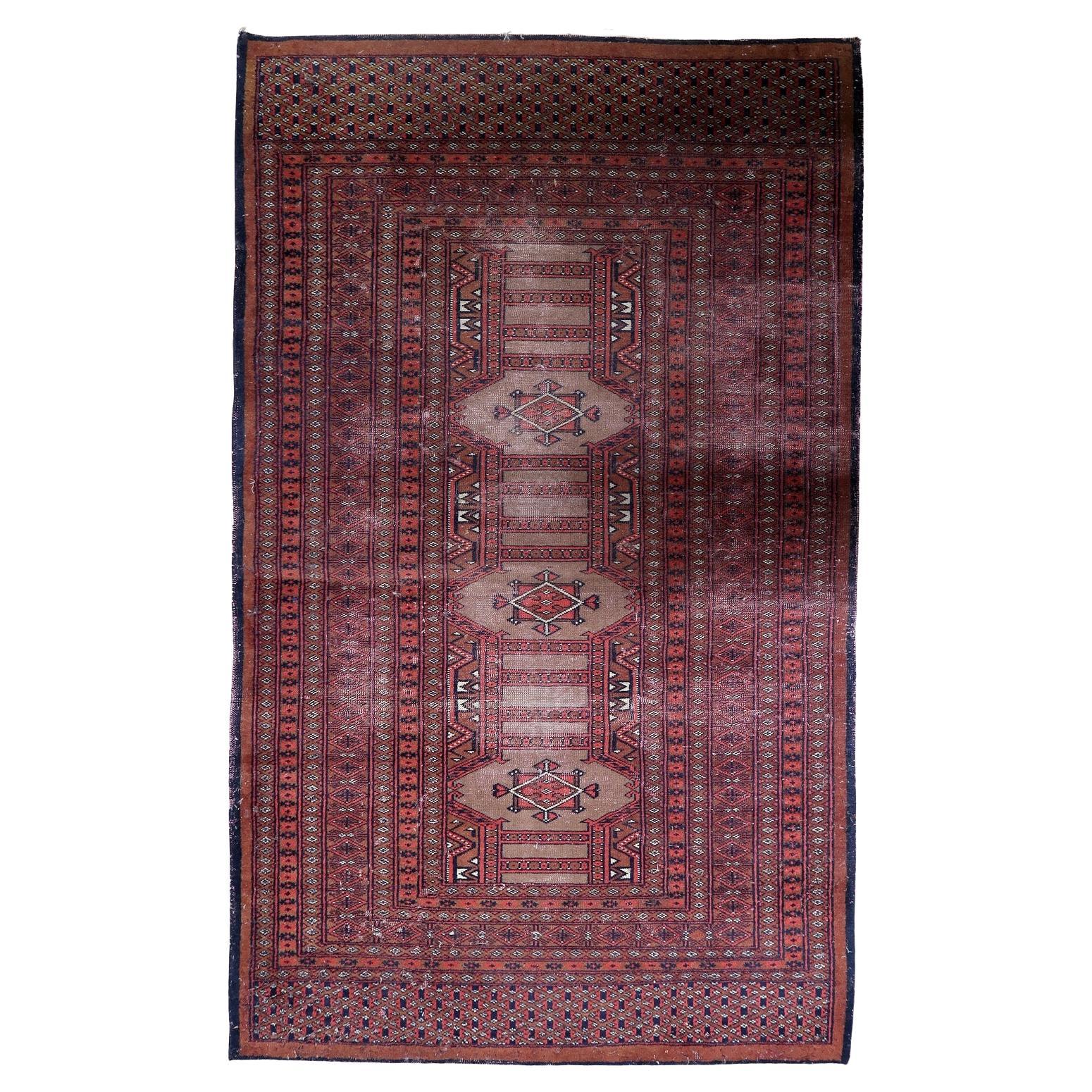 Vintage Uzbek Bukhara rug with repeating gul medallions on a deep red field.

