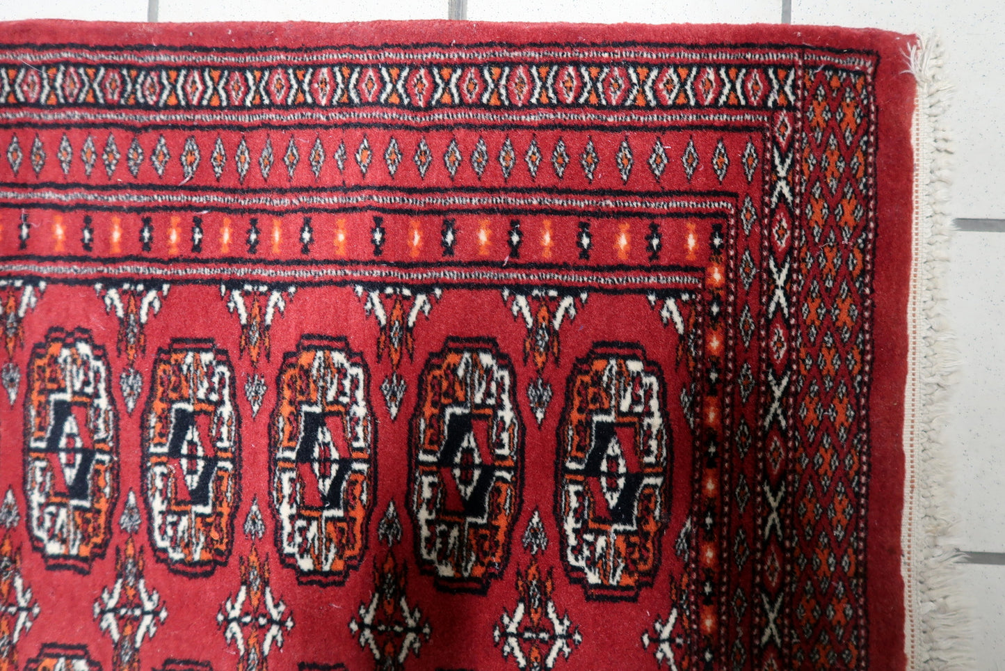 Close-up of a single octagonal gul in deep red and navy blue.

