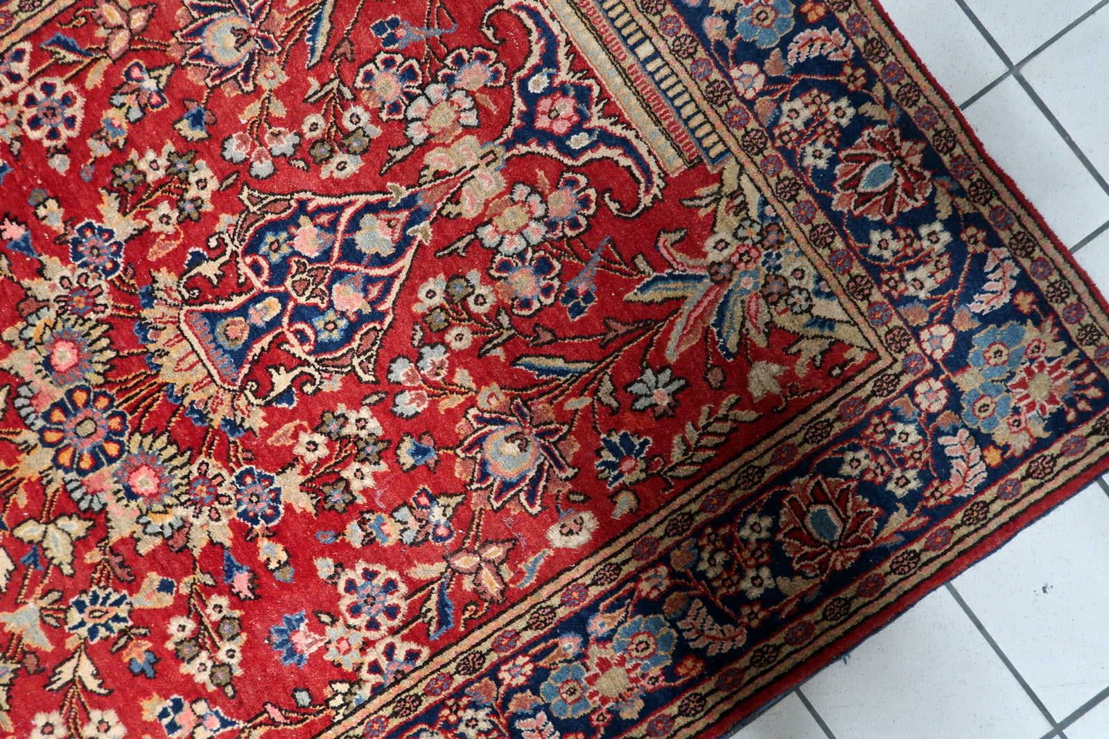 Intricate floral cartouches on the deep navy blue border.

