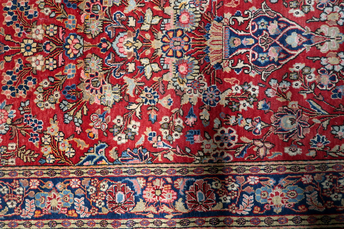 Detailed view of the intricate stylized flowers and vines on a brick-red field.

