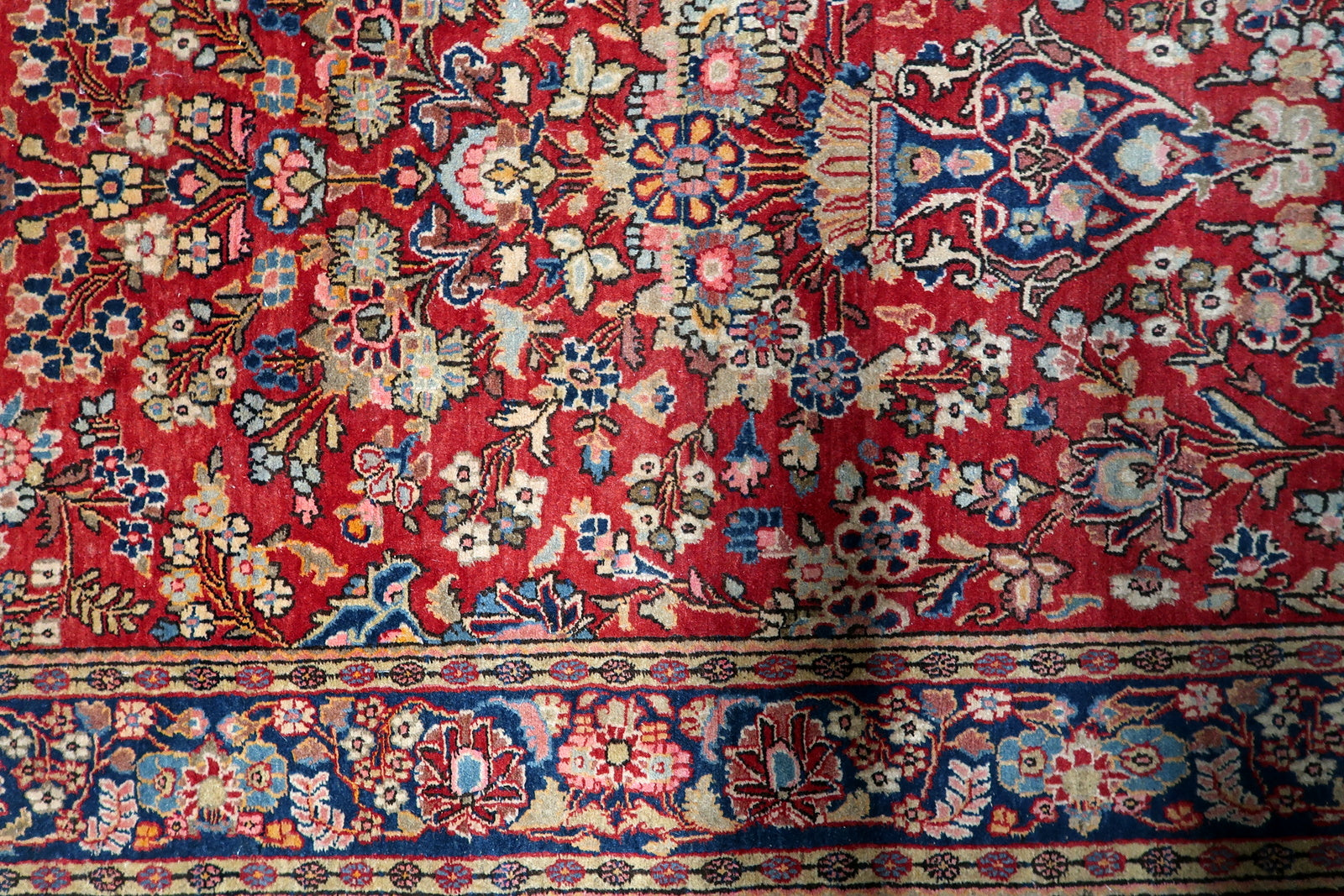 Detailed view of the intricate stylized flowers and vines on a brick-red field.

