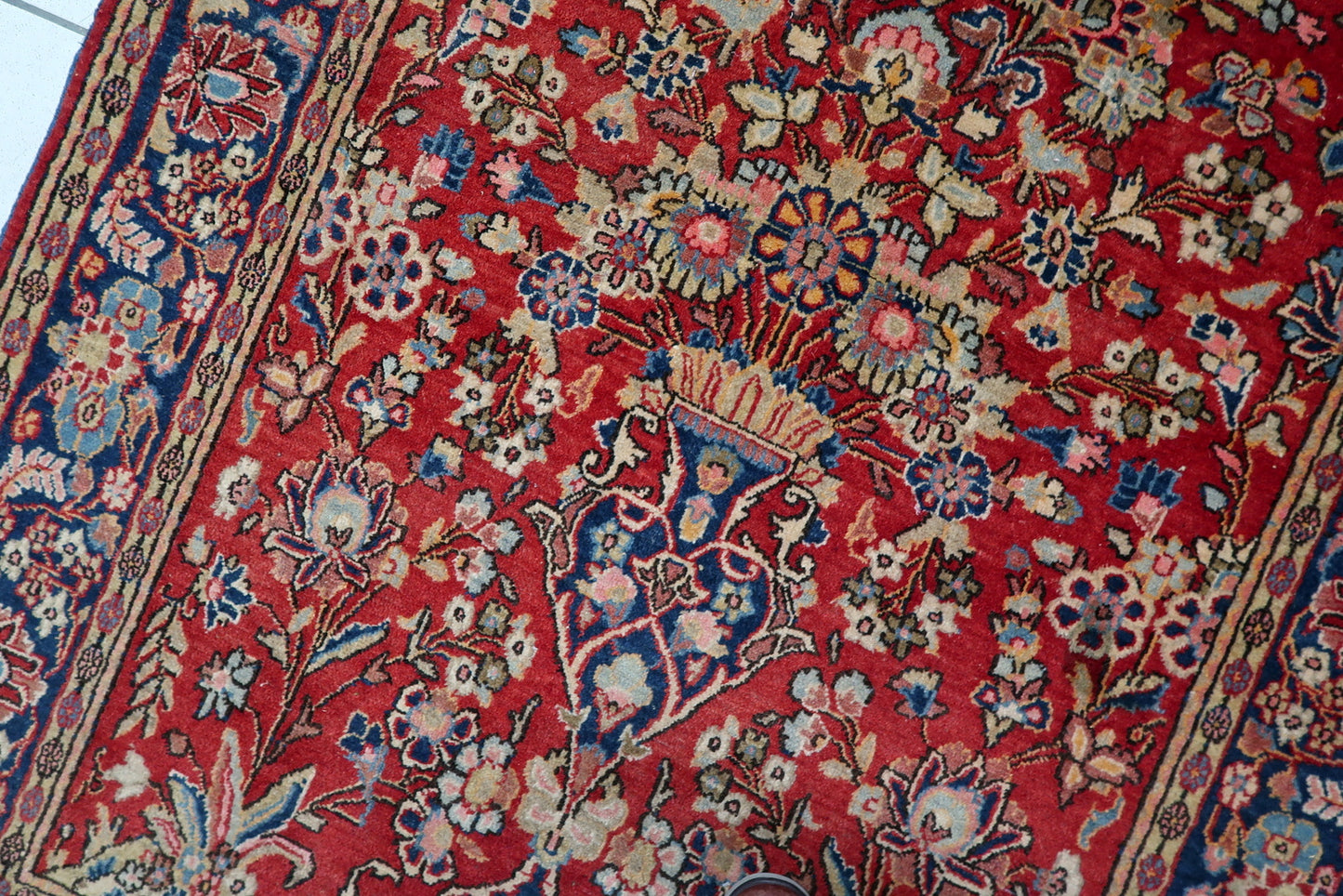 Ornate floral cartouches on the deep navy blue border.

