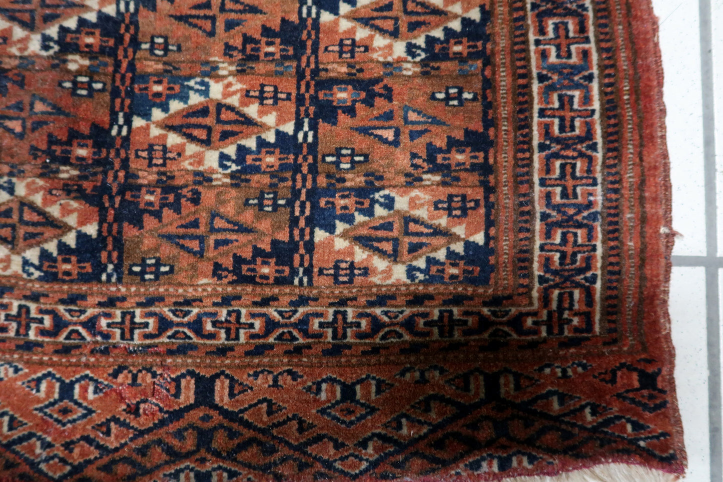 Close-up of angular tribal patterns on brick red background

