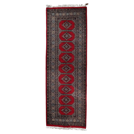Full top view of the mid-century Uzbek runner showing the rows of graphic gul motifs.


