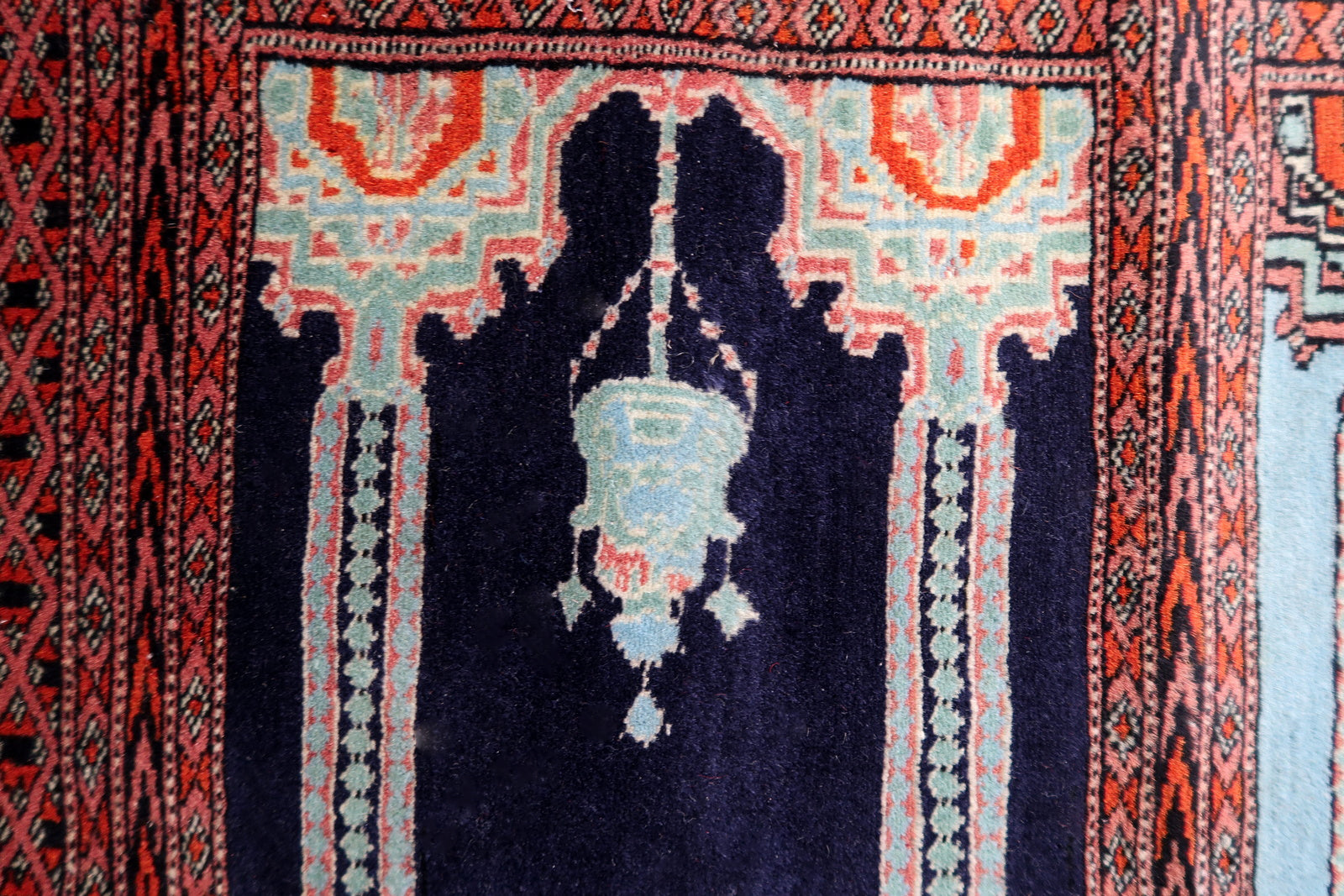 Close-up on a floral or symbolic element contained within a mihrab arch.

