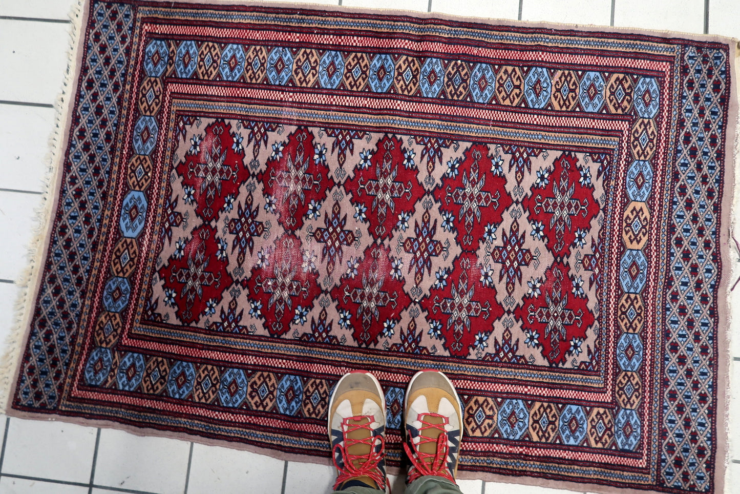 1920s Uzbek tribal rug featuring a rhythmic all-over pattern of crimson medallions on a soft beige ground.

