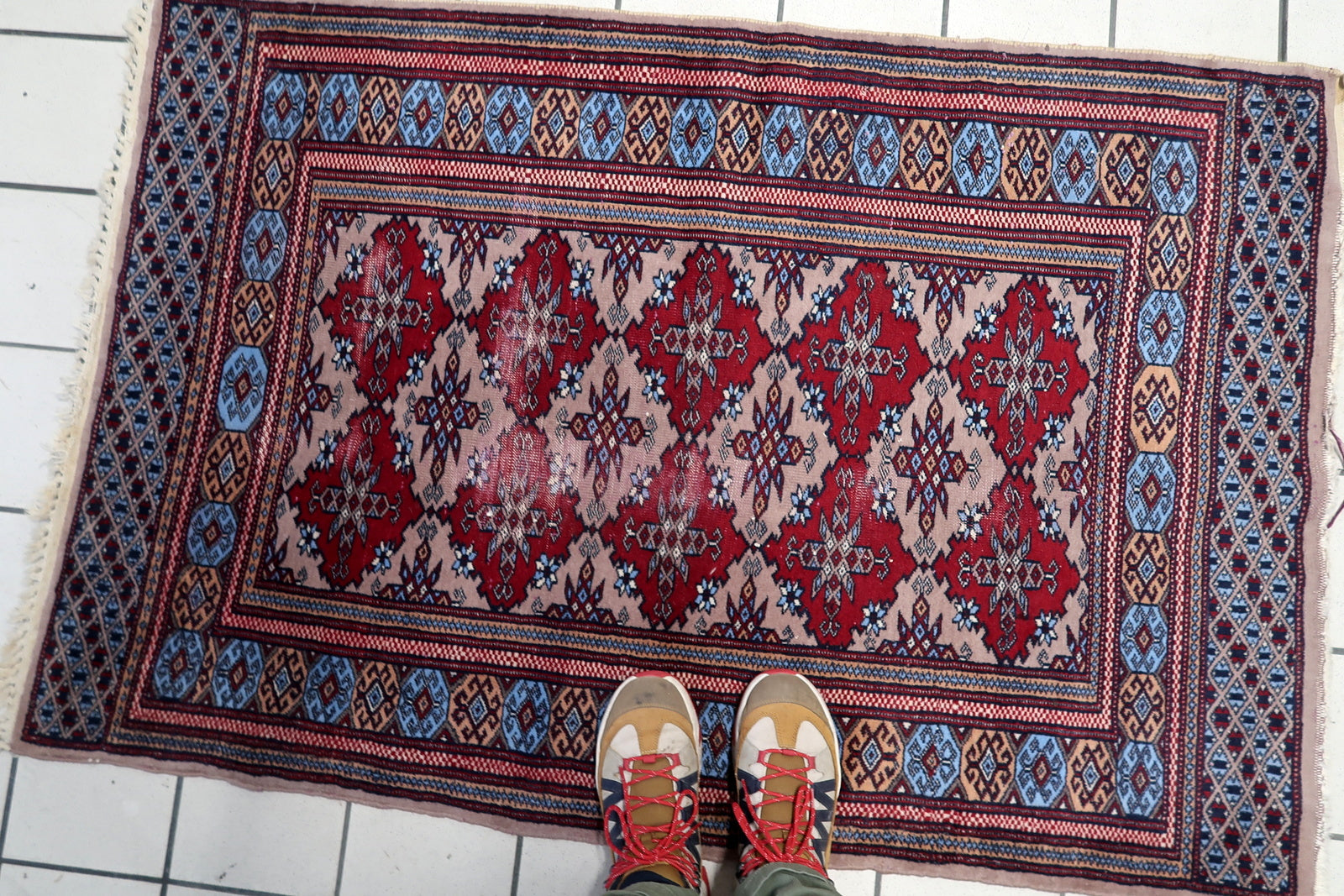 1920s Uzbek tribal rug featuring a rhythmic all-over pattern of crimson medallions on a soft beige ground.

