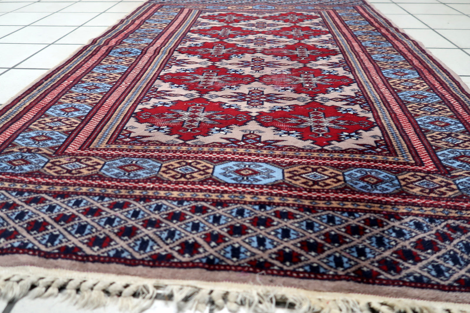 Hand-woven Central Asian rug with intricate border details, including navy, burgundy, and cream guard stripes.

