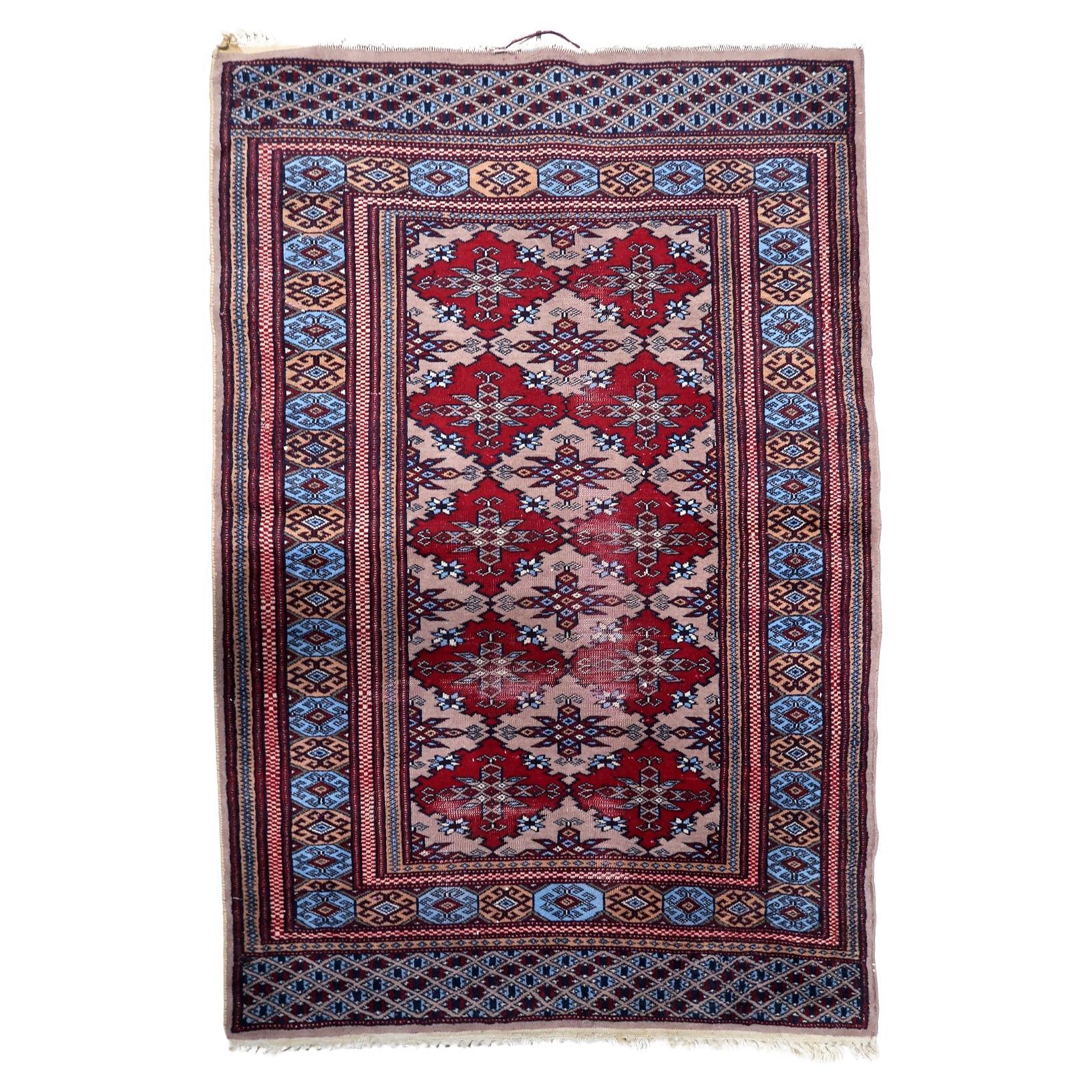 Antique Uzbek Bukhara rug from the 1920s featuring repeating crimson diamond medallions on a beige field with geometric borders.


