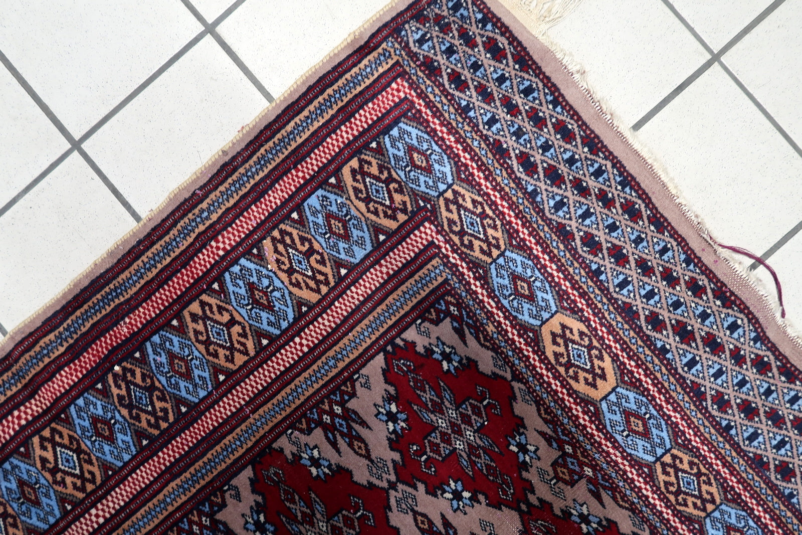Vintage 1920s Bukhara rug in distressed condition, showcasing traditional diamond guls and octagonal motifs in natural dyes.

