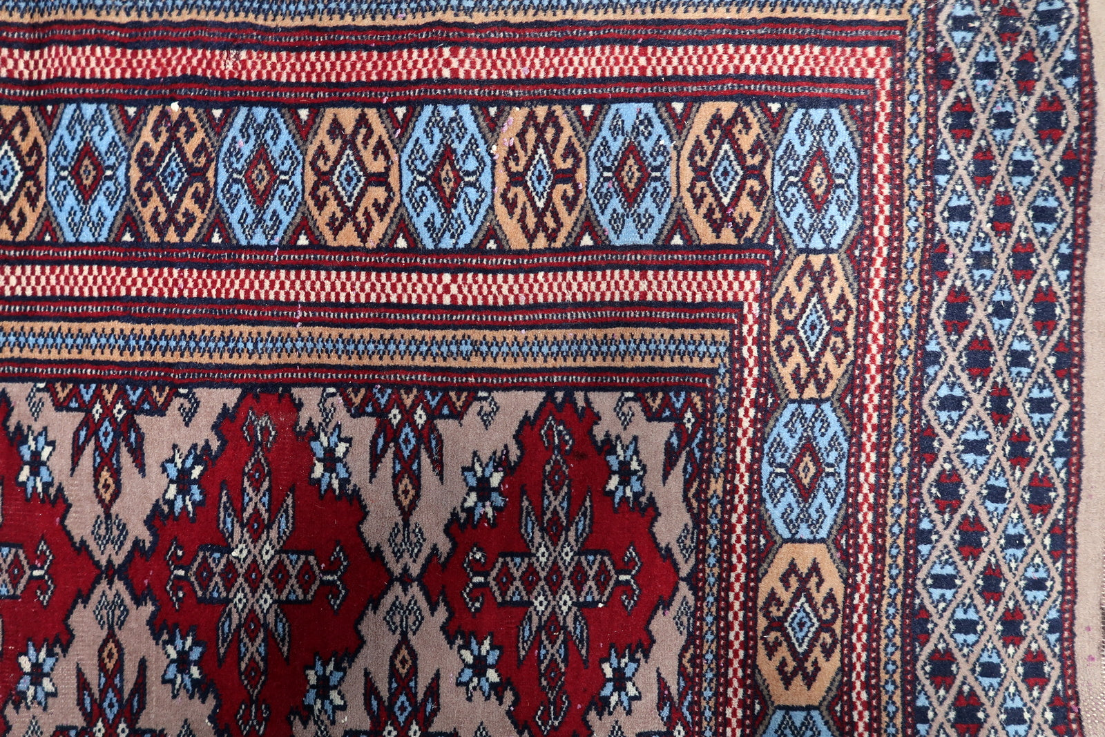 Antique Uzbek rug with a harmonious palette of crimson, navy, and gold, framed by multiple guard borders and tribal designs.

