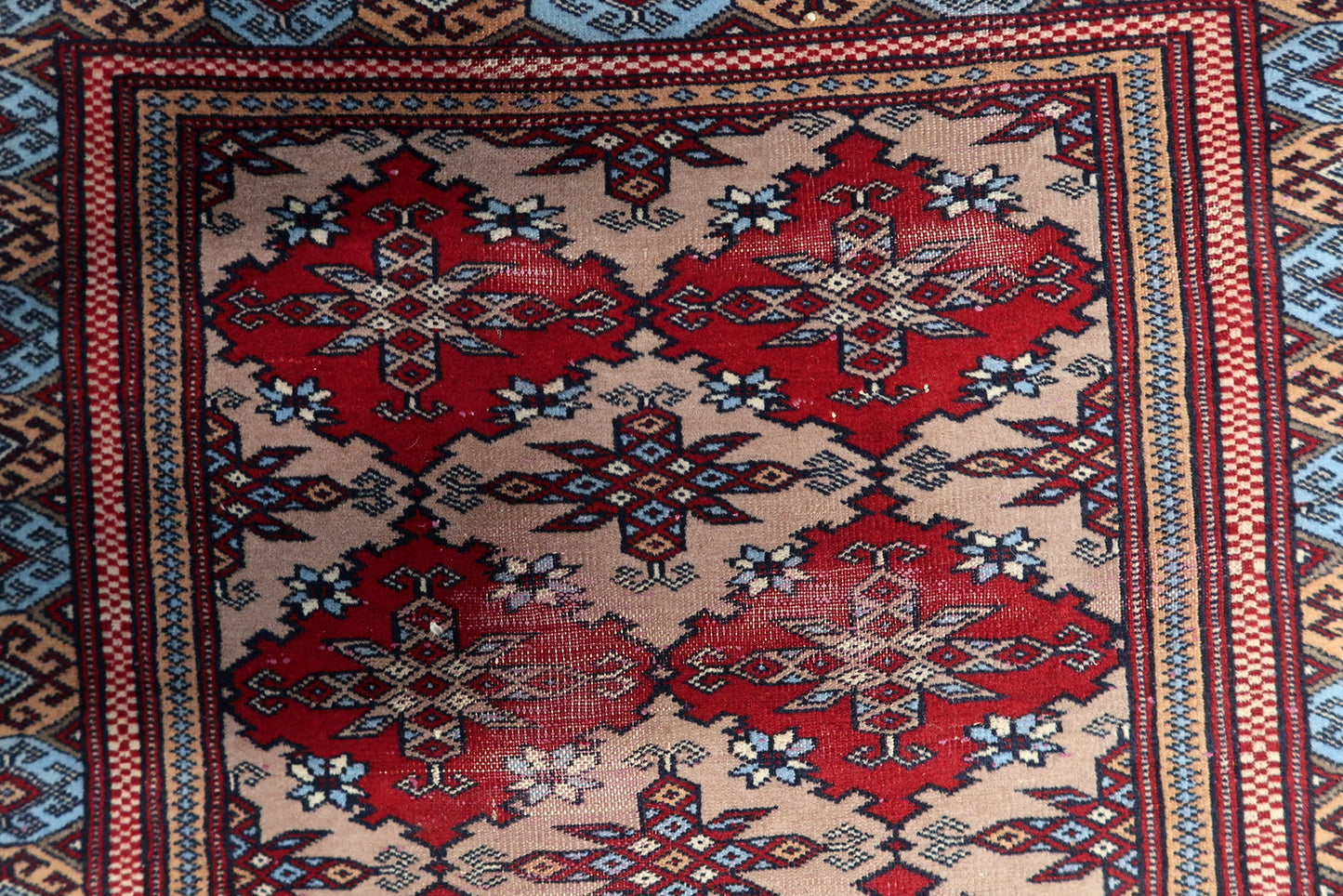 Geometric wool rug from the Bukhara region with repeating diamond medallions and vibrant blue octagonal accents.

