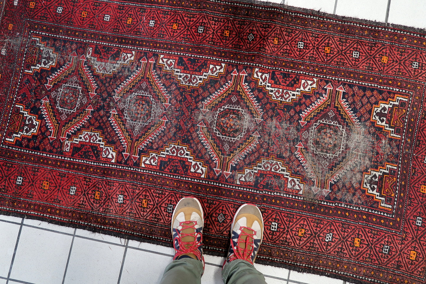 Hand-woven nomadic rug from Afghanistan's Baluch region with classic diamond medallion design.

