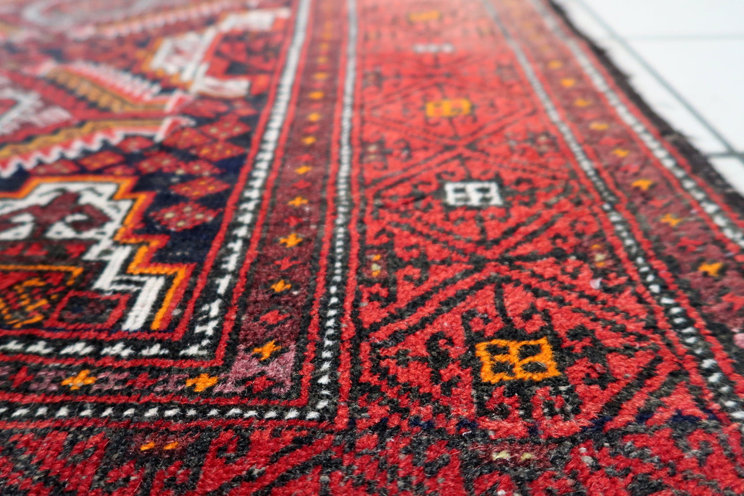 Vintage wool rug with distressed low-pile areas revealing nearly a century of authentic use.

