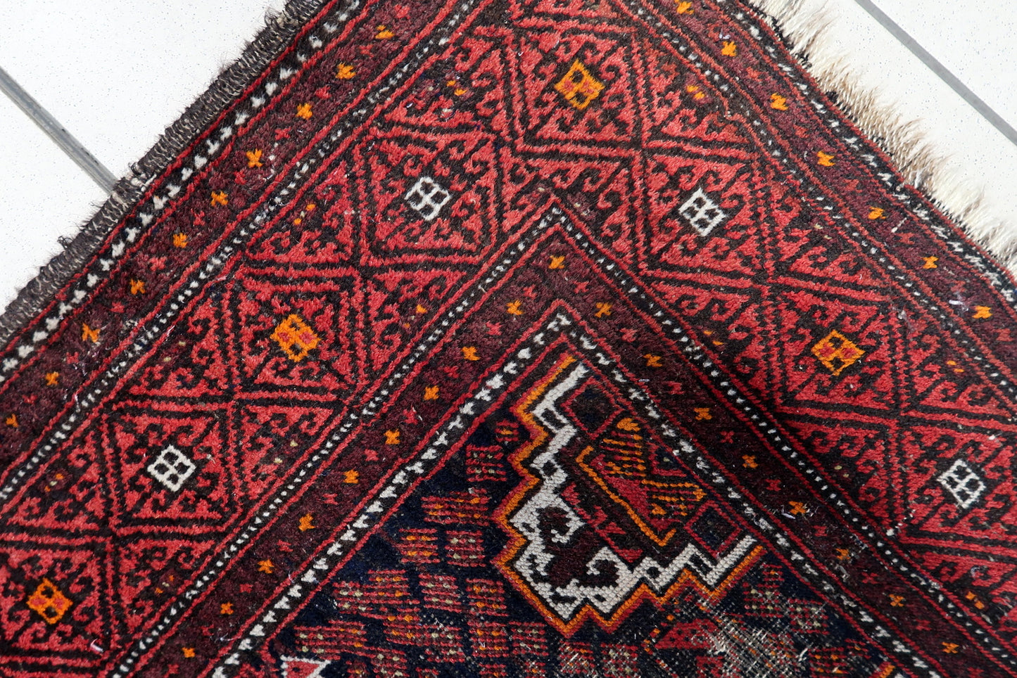 Vintage 1920s Baluch runner with striking white-outlined diamond medallions and traditional hooked motifs.

