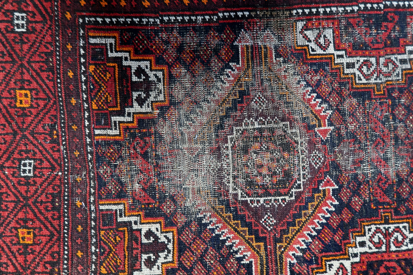 Close-up of a Central Asian tribal rug with angular hooked diamonds and intricate interior geometric patterns.

