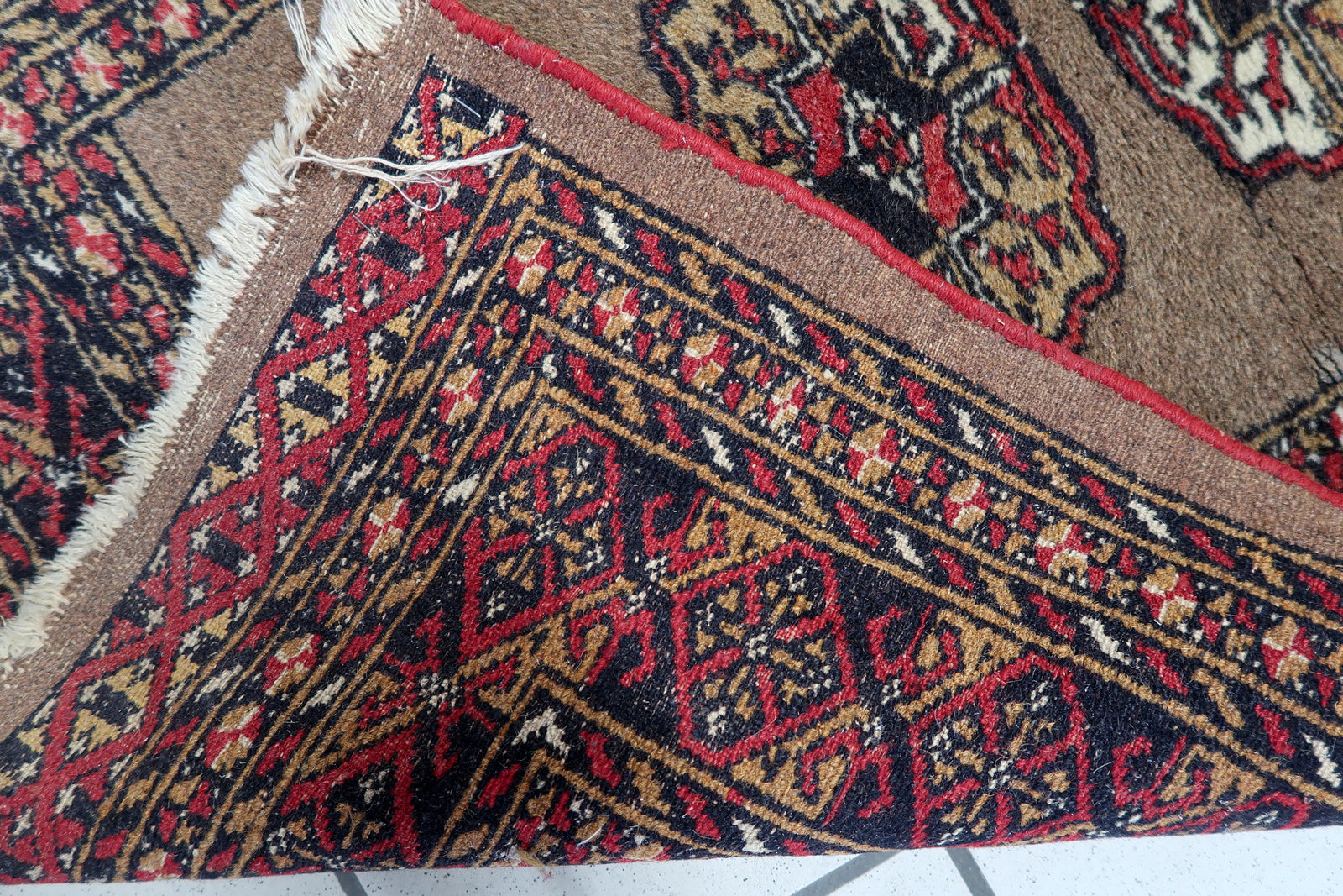 Hand-woven nomadic rug featuring classic Bukhara design elements and stylized floral motifs.

