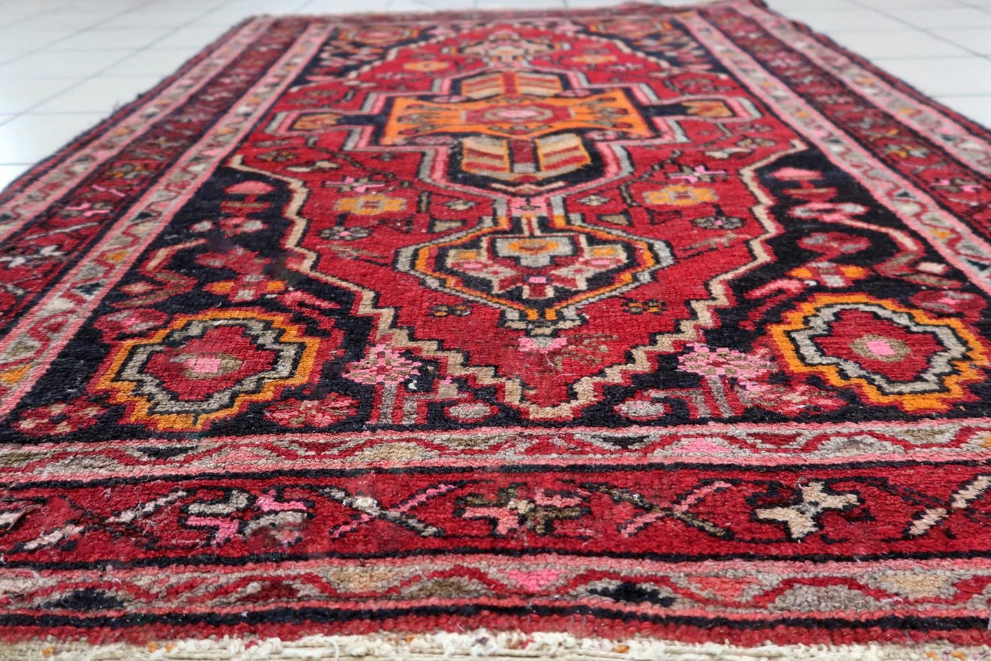 Hand-knotted Persian rug with multiple medallions and intricate border details in soft pink and burgundy.

