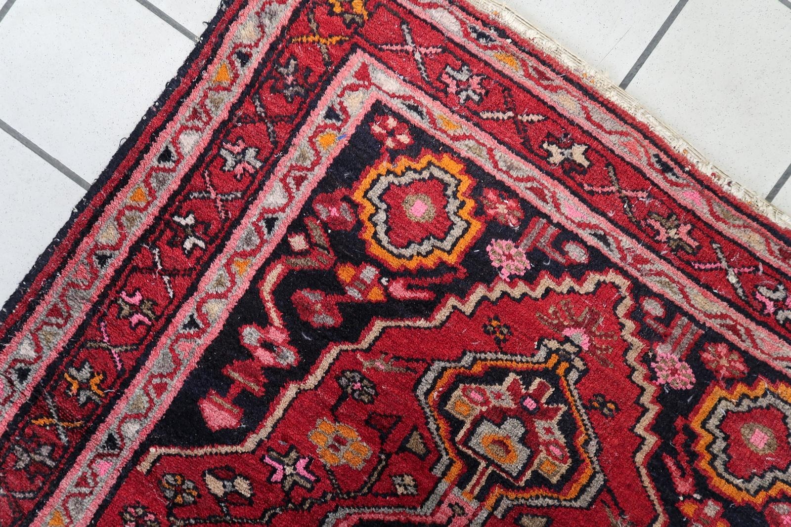 Vintage 1920s Persian rug with striking orange and cream medallions against a rich crimson red field.

