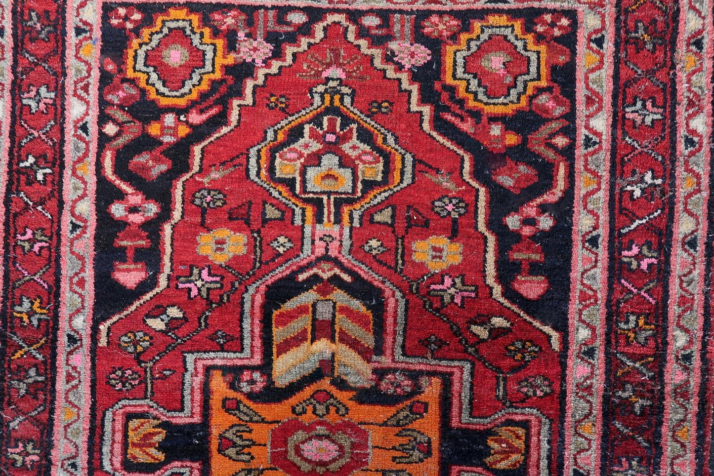 Close-up of a Persian Hamadan weaving with a large hexagonal medallion flanked by smaller geometric forms.

