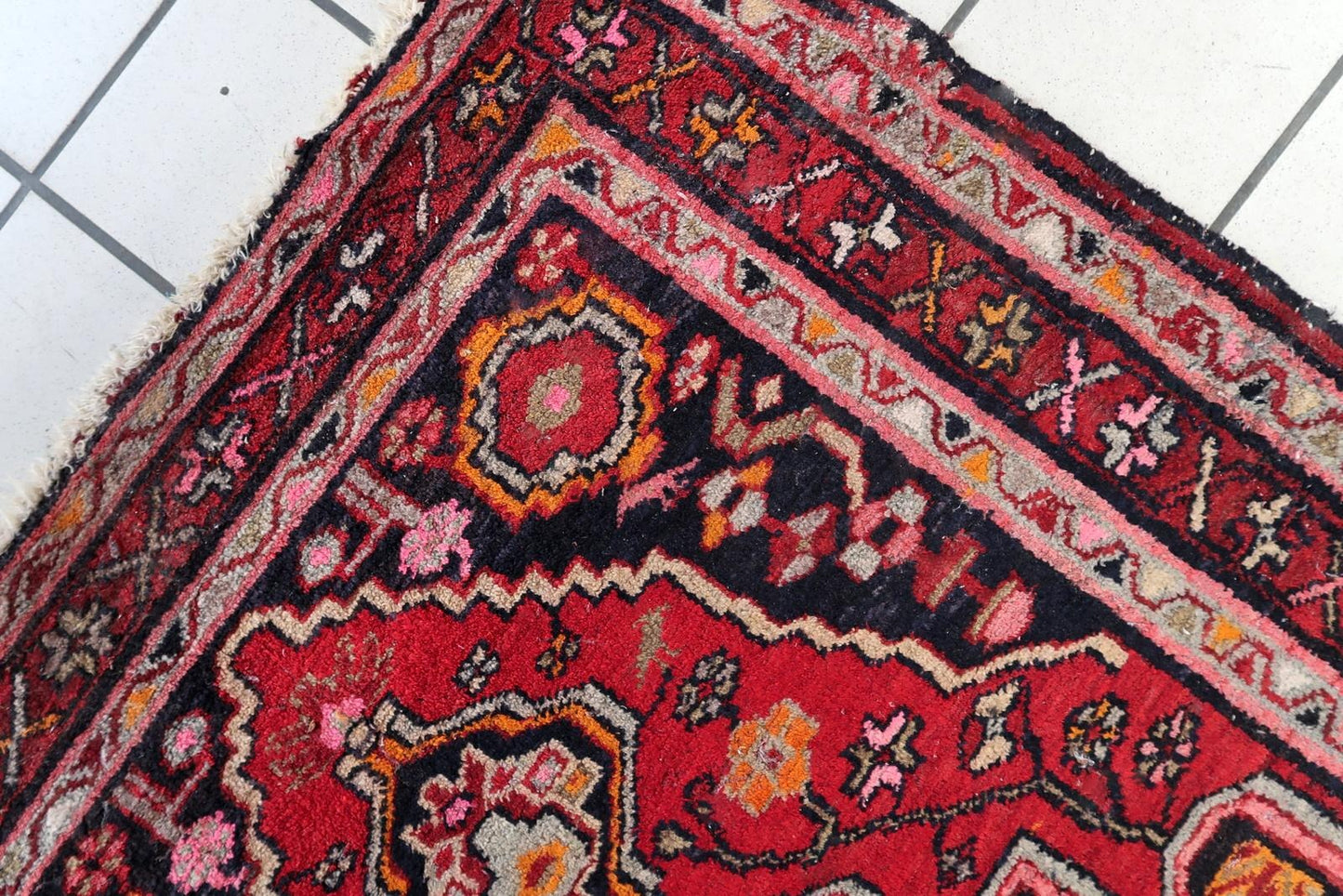 Traditional Persian village rug with stylized floral motifs, rosettes, and tribal symbols in warm earth tones.

