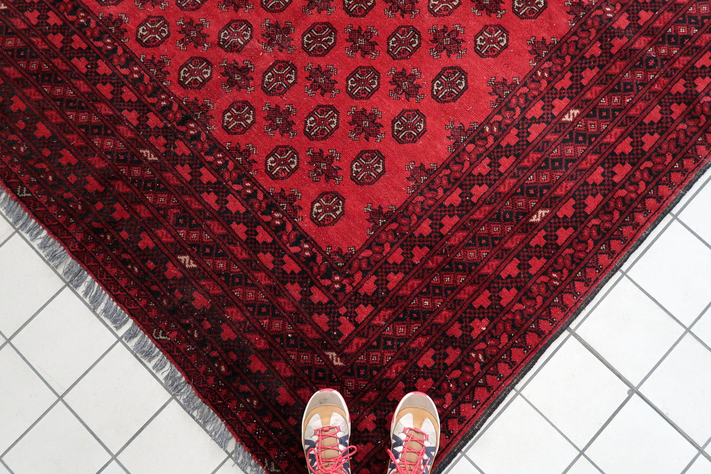 1920s vintage carpet with repeating gul medallions in coral-red and burgundy.


