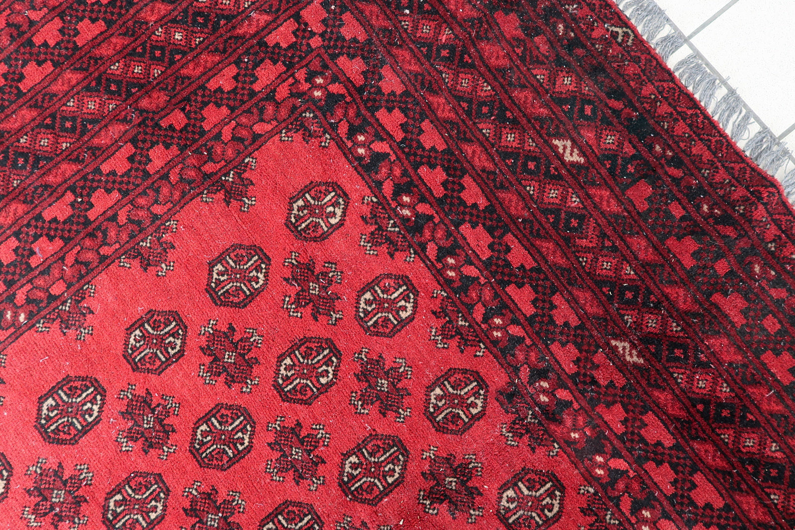 Handmade antique rug in generous room size (81.9" x 113.4") with well-preserved pile and natural dyes in coral-red, burgundy, and black.


